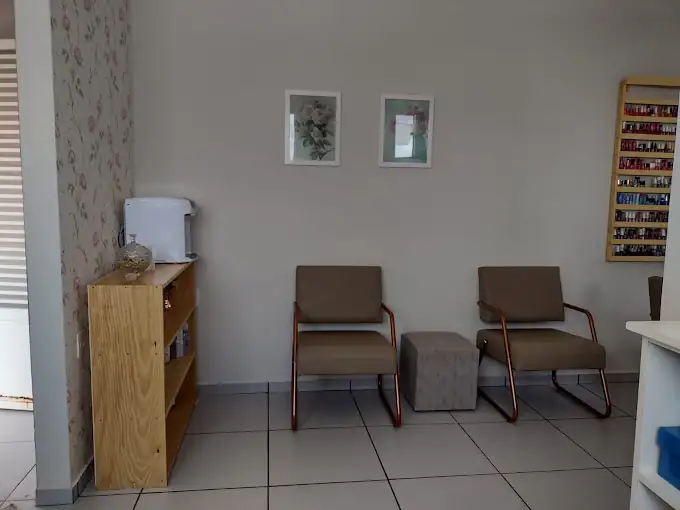 Recepção com duas poltronas, cafeteira e a parede de esmaltes ao fundo